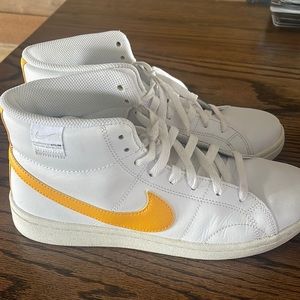 White Nikes with yellow swoosh.